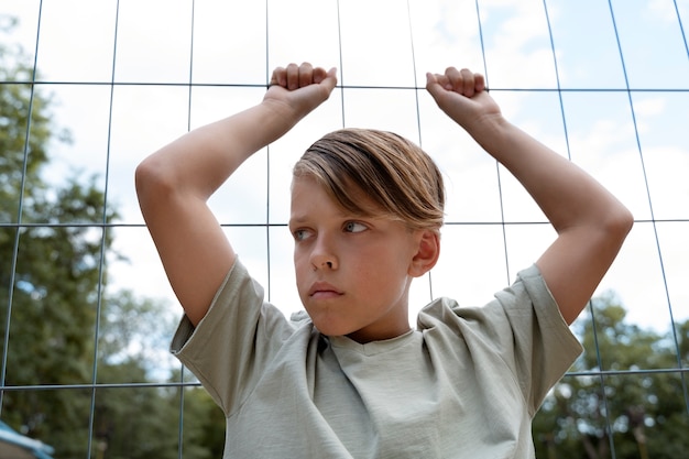 Front view sad boy near fence