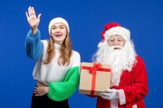Front view of santa claus along with woman holding present on blue wall