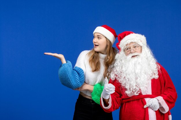 Front view santa claus along with young female standing on blue desk new year holiday color