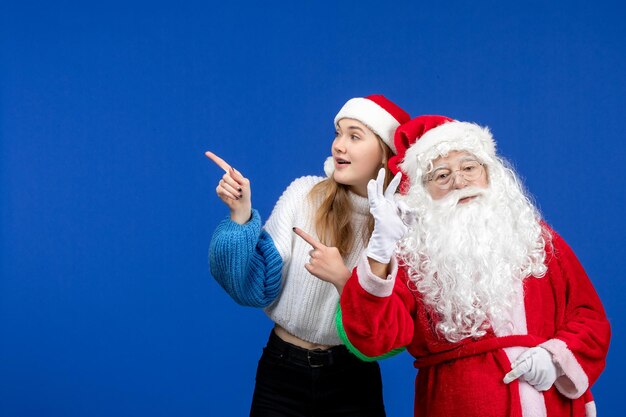 Вид спереди санта-клауса вместе с молодой женщиной, стоящей на синем новогоднем празднике цветных рождественских эмоций