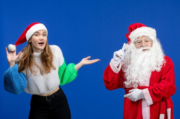 青い新年の休日モデルのクリスマスに立っている若い女性と一緒に正面図のサンタクロース