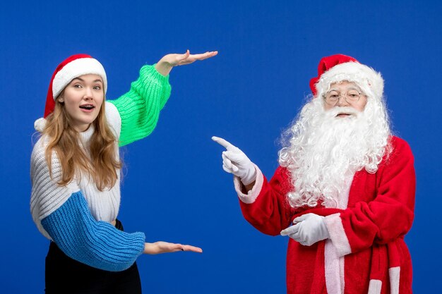 Vista frontale babbo natale insieme alla giovane donna in piedi sul blu