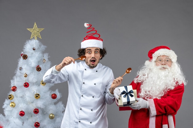 Free photo front view santa claus around holiday attributes with male cook