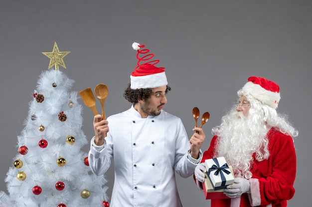 Free photo front view santa claus around holiday attributes with male cook