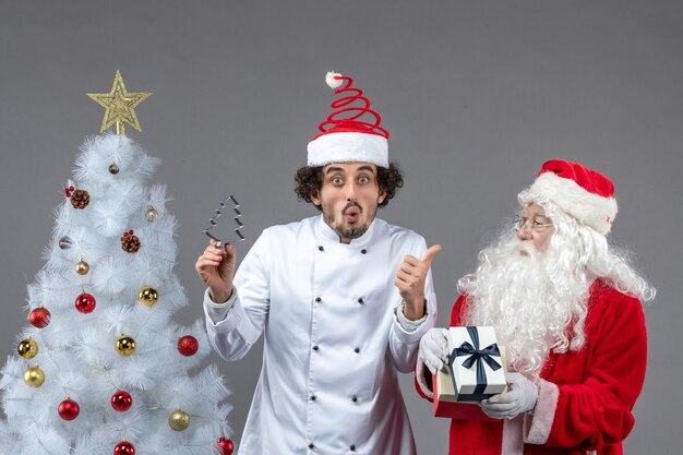 Vista frontale babbo natale intorno all'albero delle vacanze con cuoco maschio