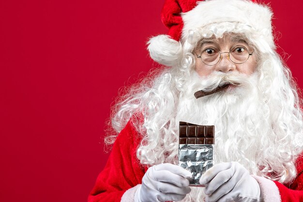 Front view santa claus biting chocolate bar