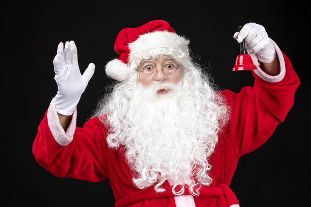 Front view santa claus in classic red suit holding bell