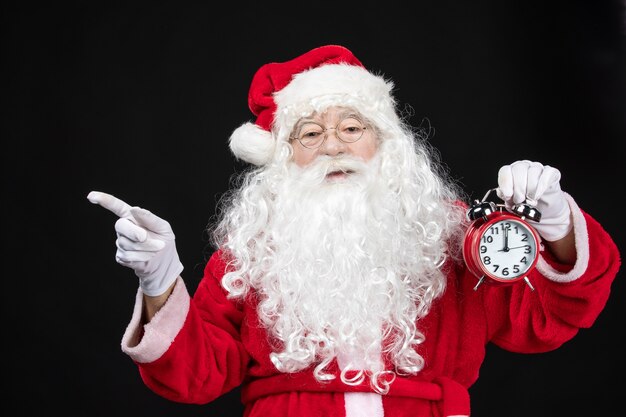 Front view santa claus in classic red suit holding clocks