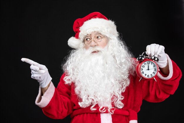 Front view santa claus in classic red suit holding clocks