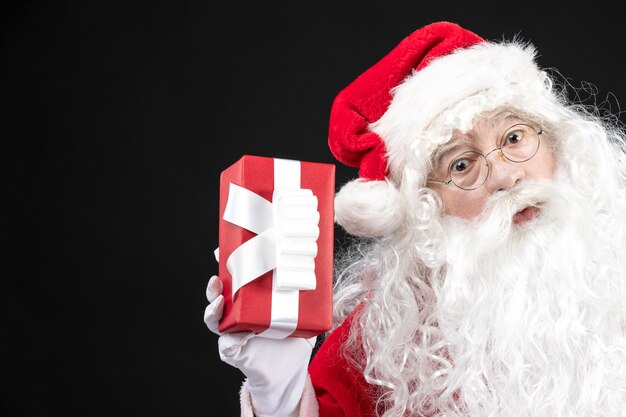 Front view santa claus in classic red suit holding present