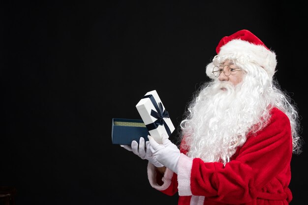 Front view santa claus in classic red suit opening present