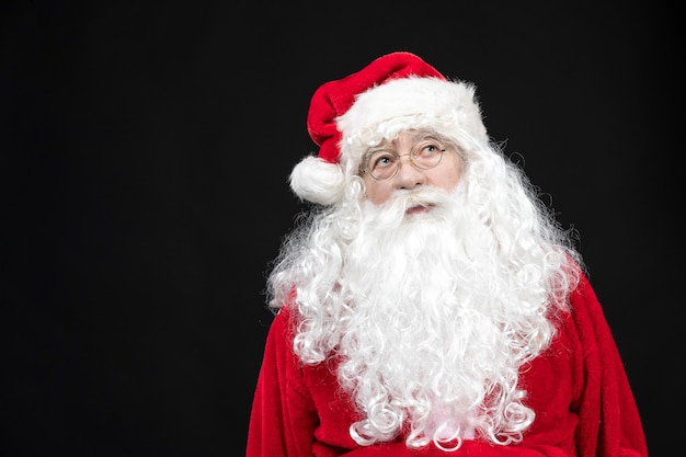 Front view of santa claus in classic red suit with white beard on black wall