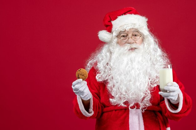 Front view santa claus eating biscuits and drinking milk