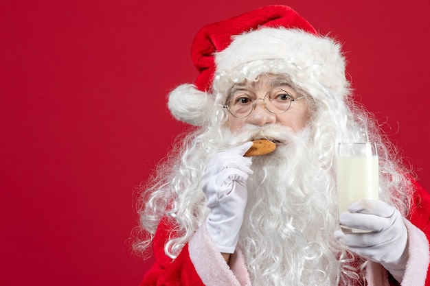 Foto gratuita vista frontale babbo natale che mangia biscotti e beve latte