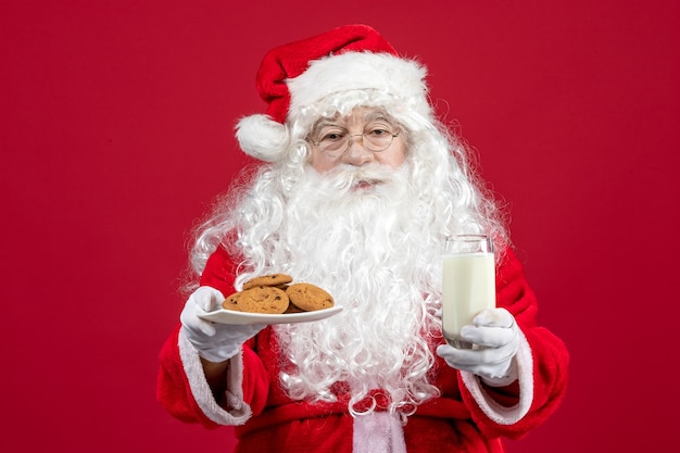 Front view santa claus holding biscuits and glass of milk