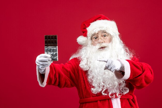 Foto gratuita vista frontale babbo natale che tiene la barretta di cioccolato