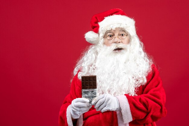 Front view santa claus holding chocolate bar
