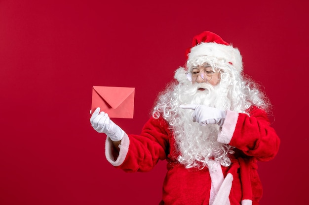 Front view santa claus holding envelop with wish letter from kid on red emotion new year gift xmas holiday