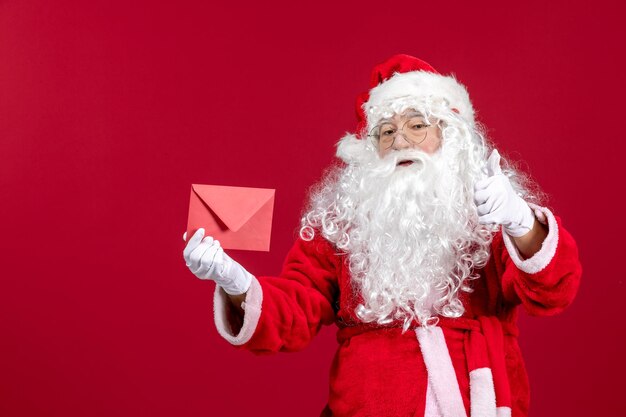 Front view santa claus holding envelop with wish letter from kid on red emotion xmas new year gift holiday