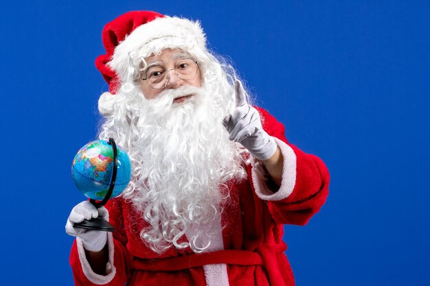 Front view santa claus holding little earth globe on a blue new year color holiday christmas