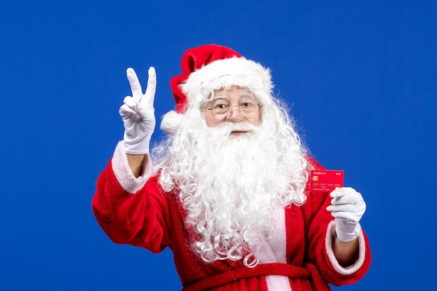 Front view santa claus holding red bank card on blue new year color holiday xmas presents