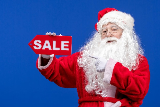 Free photo front view santa claus holding red sale writing on blue color snow holiday new year christmas