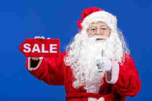 Free photo front view santa claus holding red sale writing on blue color snow holidays new year christmas