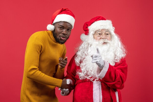 Front view of santa claus interacting with young man on a red wall