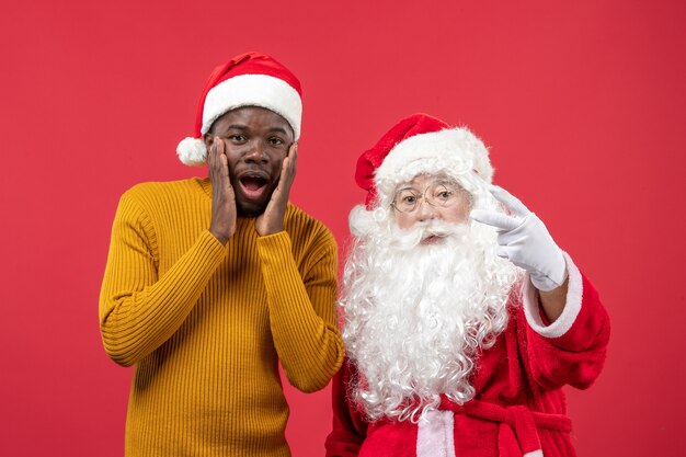 Front view of santa claus interacting with young man on red wall
