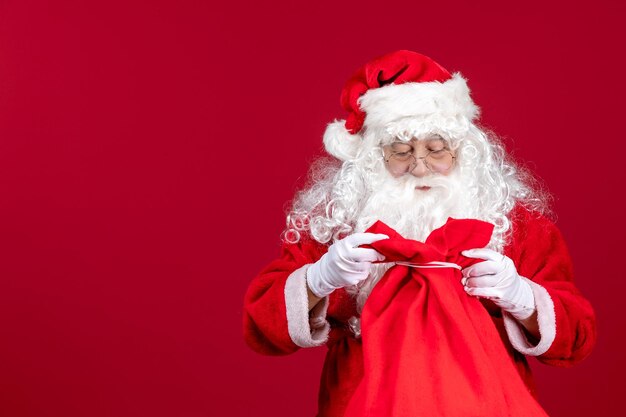 Санта-клаус, открывающий мешок, полный подарков для детей на красный праздник, вид спереди