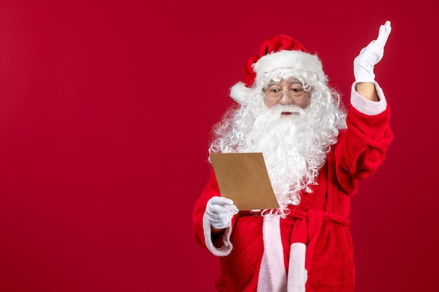 Front view santa claus reading letter from kid on a red present xmas holiday emotion
