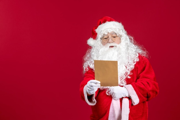 Front view santa claus reading letter from kid on red present xmas holiday emotion