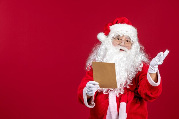 Вид спереди санта-клауса, читающего письмо от ребенка на красном подарке, рождественские праздничные эмоции