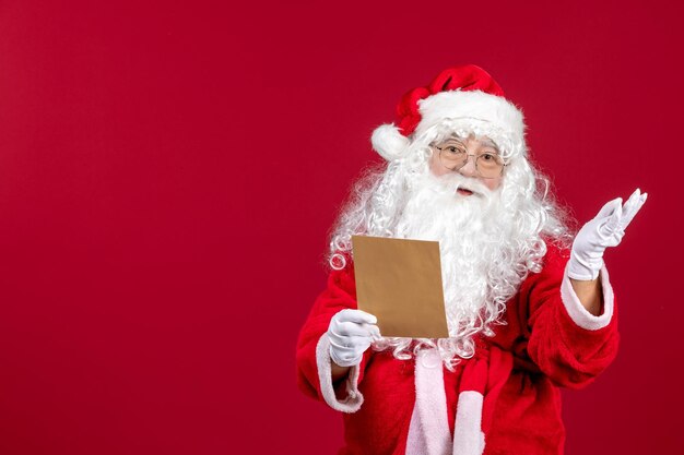 Front view santa claus reading letter from kid on red present xmas holiday emotions