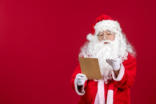 Front view santa claus reading letter from kid on red present xmas holidays emotion