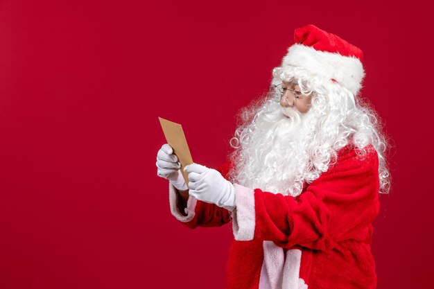 Front view santa claus reading letter from kid on red xmas holiday emotion