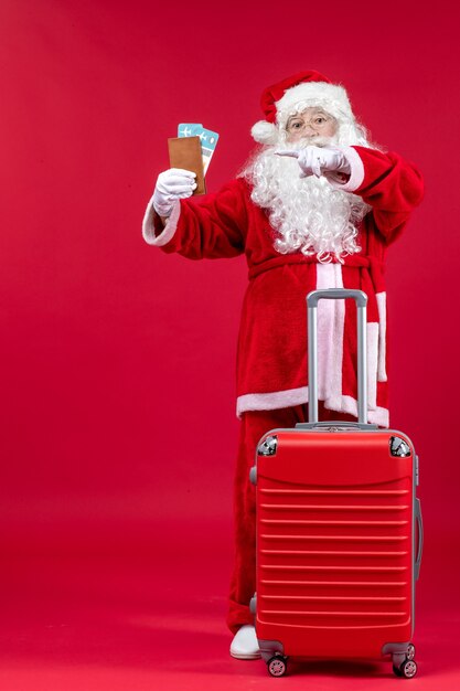 Front view of santa claus with bag holding tickets and preparing for trip on red wall