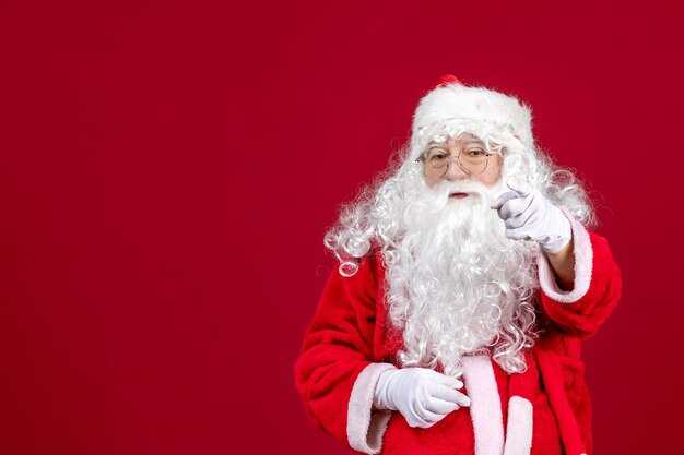 Front view santa claus with classic white bear and red clothes pointing on red xmas new year holiday emotion