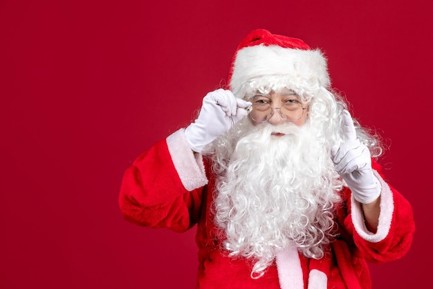 Foto gratuita vista frontale babbo natale con classico orso bianco e vestiti rossi sul pavimento rosso emozione per le vacanze di natale capodanno