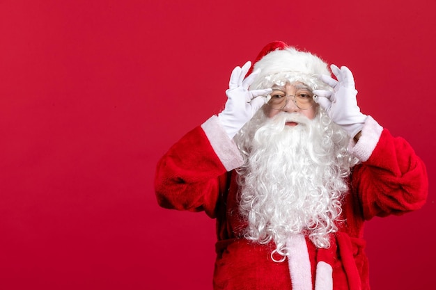 Foto gratuita vista frontale babbo natale con classico orso bianco e vestiti rossi in piedi durante le vacanze di capodanno di natale rosso