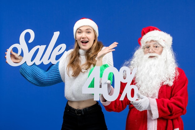 Front view santa claus with female holding sale writings on a blue holiday cold christmas new year snow