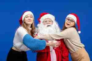 Free photo front view santa claus with females on blue cold holidays christmas new year