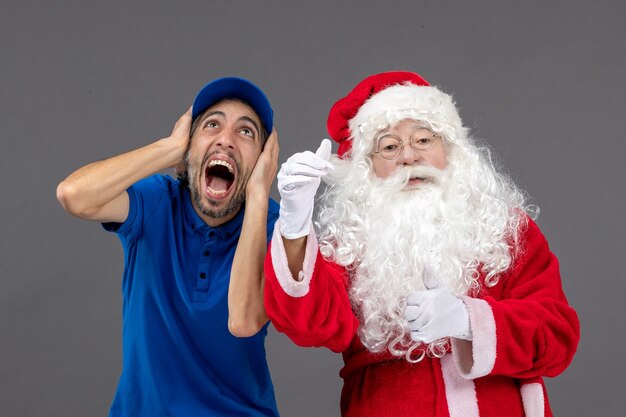 Front view of santa claus with male courier on a grey wall