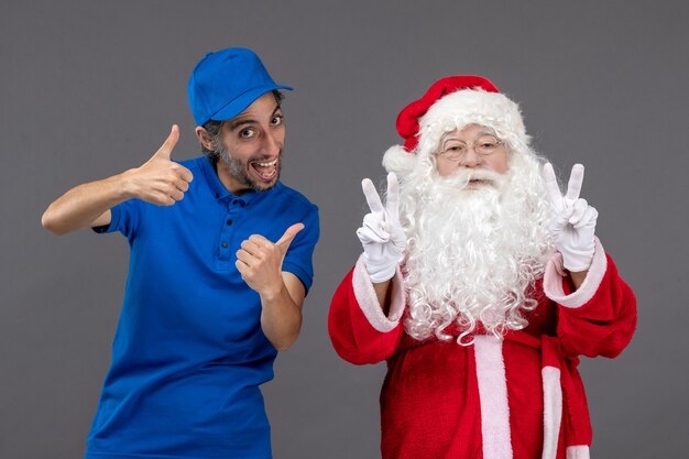 Front view of santa claus with male courier on a grey wall