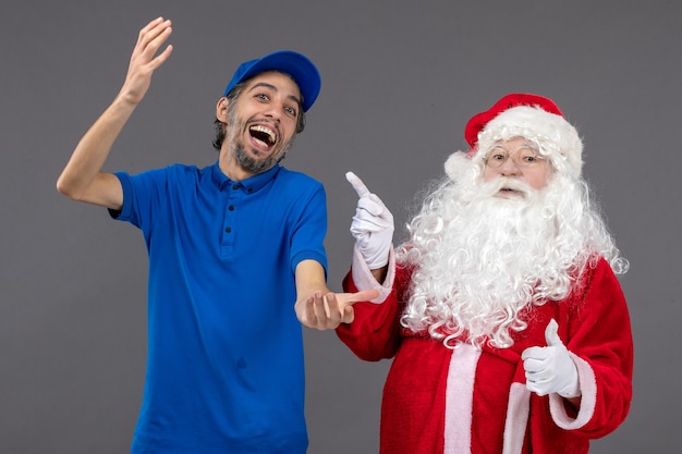 Free photo front view of santa claus with male courier on a grey wall