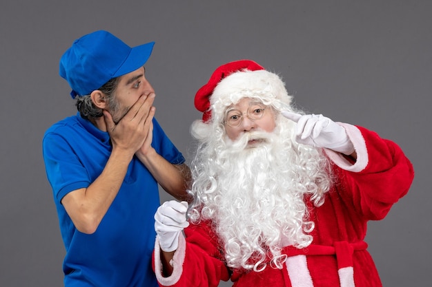 Front view of santa claus with male courier on grey wall