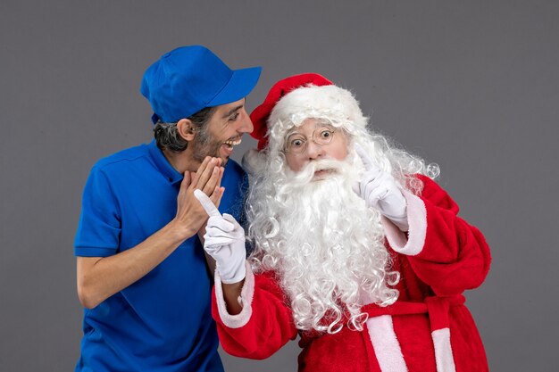 Front view of santa claus with male courier on grey wall