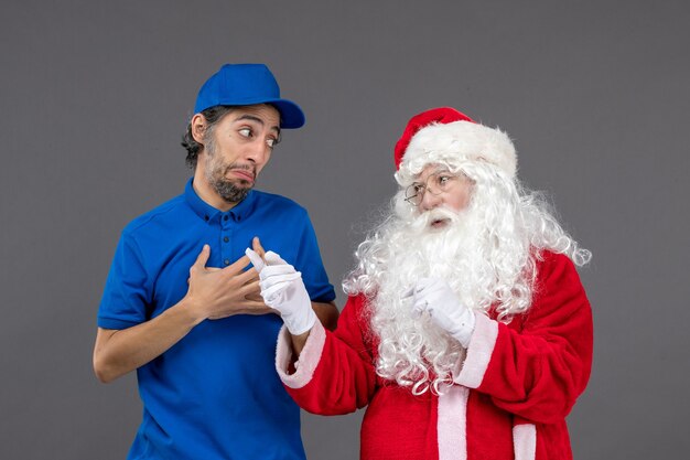 Front view of santa claus with male courier on grey wall