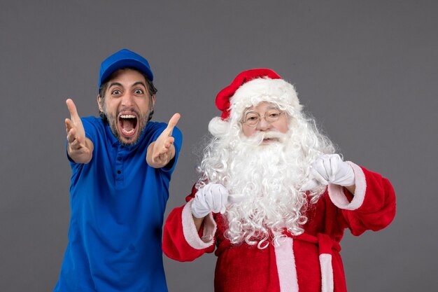 Front view of santa claus with male courier on grey wall