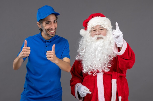 Front view of santa claus with male courier on grey wall